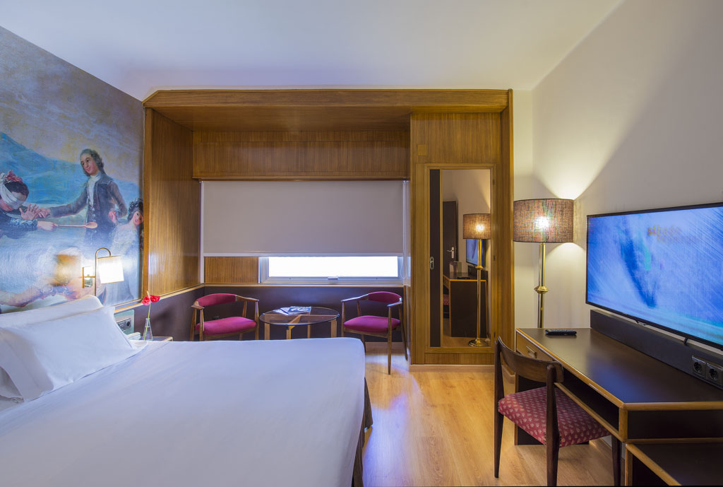 Habitación del Hotel Goya Zaragoza con cama doble, zona de estar con sillones y decoración clásica.